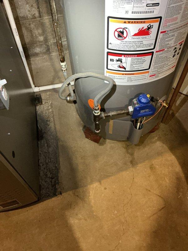 Responded to service call for leaking 40-gallon natural gas water heater (Model PROG40S-36N RH62) manufactured in March 2018. Upon inspection, identified active leak affecting entire home's hot water supply in basement utility area. Documented equipment specifications, safety labels, and installation configuration including pressure relief valve, gas connections, and copper supply lines with blue pressure regulator. Photographed unit condition, surrounding concrete floor showing water damage and staining, and proximity to HVAC system in mechanical room with concrete block walls.