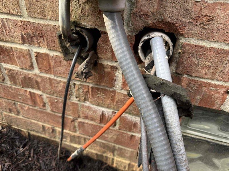Completed MVP cooling maintenance visit on 8-year-old system. Performed comprehensive inspection of outdoor condensing unit and indoor air handler components. Checked refrigerant levels, electrical connections, and control board operation. Inspected blower assembly and verified proper airflow. Examined exterior utility penetrations through brick wall, noting multiple PVC lines, electrical conduit, and proper sealing around penetration points. Replaced thermostat batteries per customer request and provided instruction on future battery replacement procedure. All system components operating within normal parameters. Unit tested and left in proper working condition.