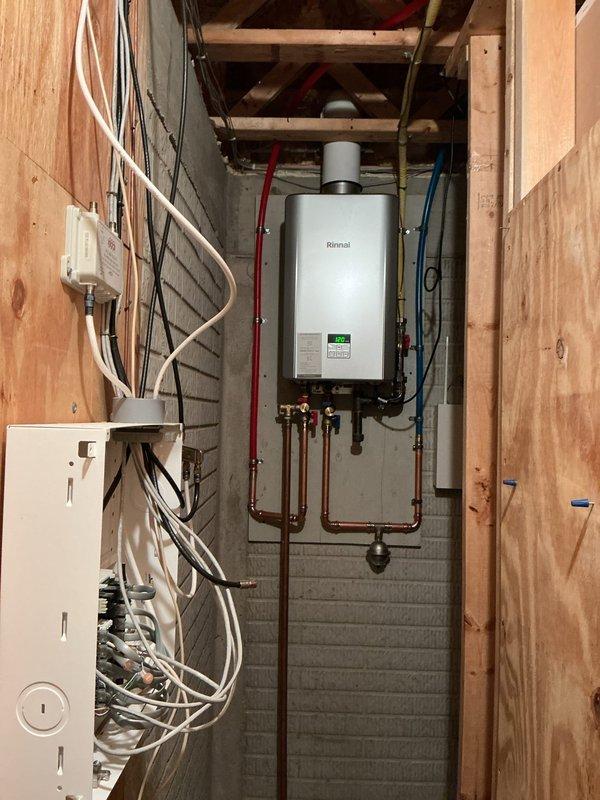 Removed existing Rinnai RL75 tankless water heater and replaced with new Rinnai RE180 unit in unfinished basement mechanical room. Installation included connecting copper hot and cold water supply lines with shutoff valves, installing PVC exhaust venting system, and completing all necessary electrical connections. Verified proper operation of new tankless water heater upon completion, ensuring adequate water flow and temperature control functionality.