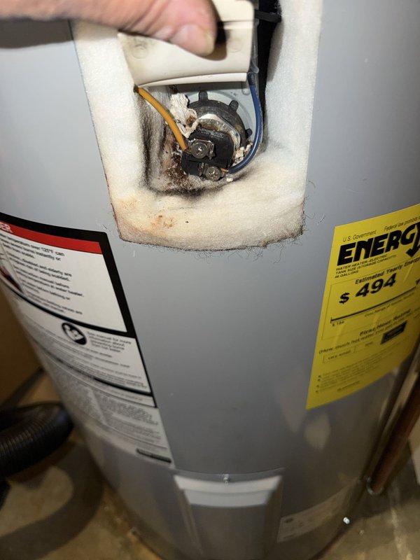 Responded to water heater service call at residential property. Upon arrival, inspected Lochinvar brand tanked water heater, approximately two years and nine months old based on manufacture date. Unit located in basement utility area with standard copper supply line connections and proper venting configuration.

Removed top access panel to assess internal components and heating elements. Inspection revealed significant sediment accumulation and corrosion deposits around heating element assembly and within tank opening. Brown discoloration present on internal foam insulation indicating mineral buildup from water quality issues. Multiple wire connections to heating element showed signs of exposure to moisture and sediment.

Documented unit condition with photographs showing overall installation and internal component deterioration. Verified warranty status with homeowner, who indicated he is second owner of property. Based on manufacture date and typical warranty terms, discussed coverag
