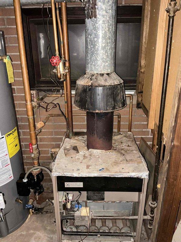Conducted estimate for replacement of existing gas boiler system showing significant age and deterioration, including heavily rusted components and weathered ductwork connections. Assessment confirmed boiler replacement needed in current location without relocation, with existing copper piping infrastructure and gas lines to remain in place for connection to new unit.