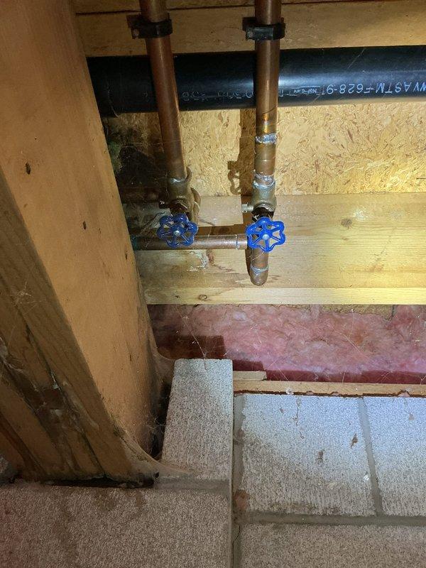 Responded to water leak complaint affecting multiple floors of residence. Upon inspection, identified corroded fitting on 5-year-old water heater in basement area. Documented corrosion damage with photographs showing deteriorated brass connections at copper supply lines with blue-handled shutoff valves. 

Traced active leak along vertical water line running from basement through to second story. Located water damage and staining on OSB sheathing in upper level, indicating prolonged moisture intrusion from compromised piping. Photographed evidence of water penetration showing characteristic blue-purple discoloration pattern on wall surfaces near plumbing chase.

Performed diagnostic evaluation of entire vertical supply line system including inspection of exposed copper piping, fittings, and valve assemblies in basement mechanical area. Assessed condition of connections at water heater and identified need for fitting replacement due to advanced corrosion. Recommended repairs to compromis