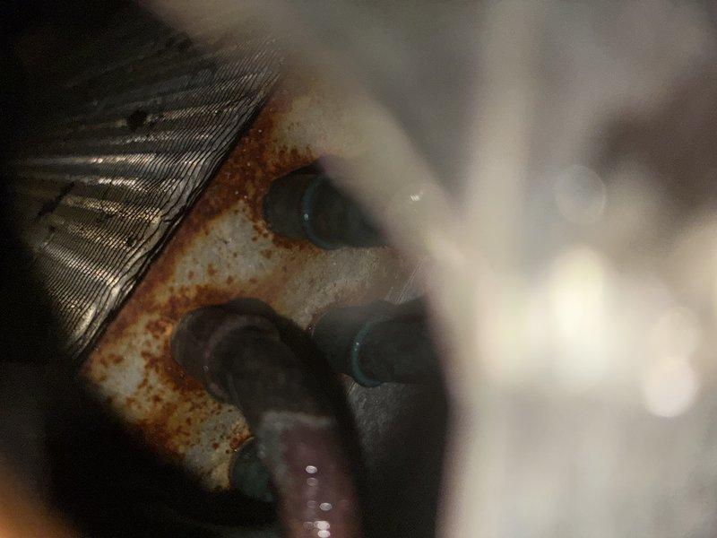 Performed preventive maintenance inspection on residential air conditioning system for established customer. Upon examination of indoor evaporator coil assembly, identified moderate to significant rust and corrosion present on metal housing components, corrugated fins, and mounting surfaces, indicating prolonged moisture exposure. Documented deterioration with photographic evidence showing oxidation patterns around connection points and along seams of ductwork. Inspected refrigerant lines, condensate drainage system, and associated mechanical components for proper operation. System functionality verified at time of service visit.