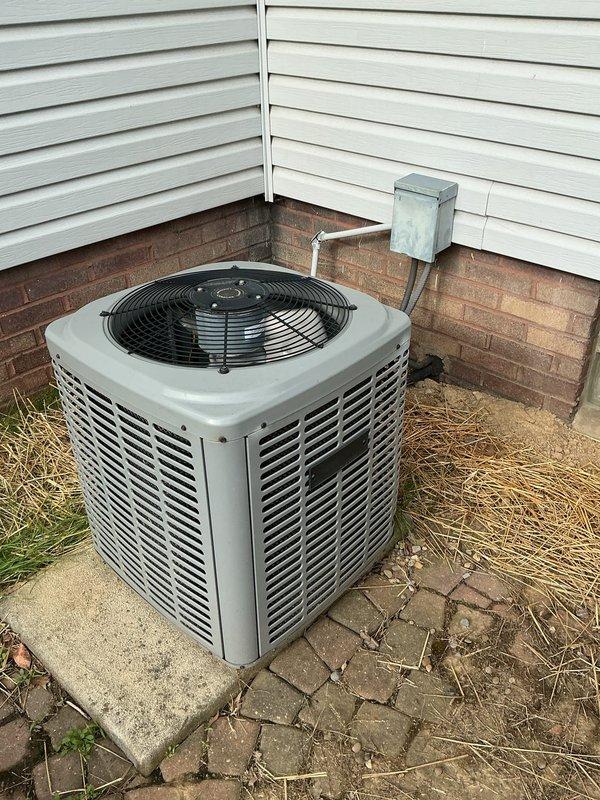 Responded to service call for air conditioning unit freezing up at the evaporator coil connection point. Upon arrival, unit was powered off as requested. Performed visual inspection of outdoor condenser unit and indoor furnace/air handler system. Condenser unit located on exterior concrete pad showed normal exterior condition with proper clearances. Indoor air handler connected to ductwork system inspected for airflow restrictions and refrigerant line issues at the A-coil joint area. System age unknown per occupant. Documented equipment condition with photographs for service records.