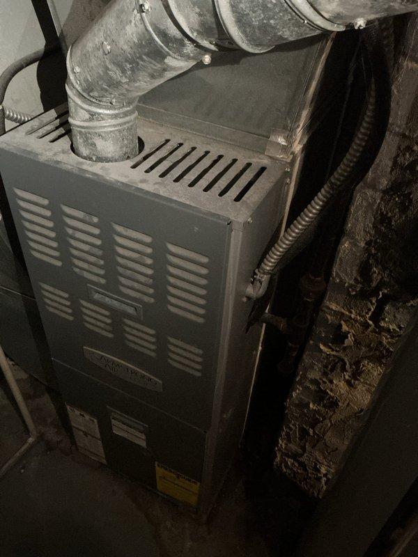 Responded to service call for air conditioning unit freezing up at the evaporator coil connection point. Upon arrival, unit was powered off as requested. Performed visual inspection of outdoor condenser unit and indoor furnace/air handler system. Condenser unit located on exterior concrete pad showed normal exterior condition with proper clearances. Indoor air handler connected to ductwork system inspected for airflow restrictions and refrigerant line issues at the A-coil joint area. System age unknown per occupant. Documented equipment condition with photographs for service records.