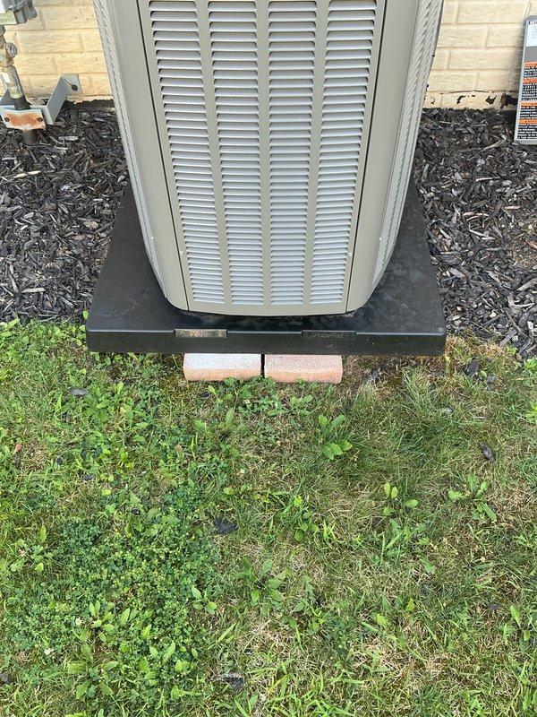 Responded to callback on 28-day-old Lennox installation experiencing loud banging noise upon startup. Diagnosed unit settling and pad instability as root cause of mechanical noise. Leveled and stabilized condenser unit using handjack tool, added gravel base material beneath existing concrete blocks and black composite pad to eliminate movement and ensure proper drainage. Verified unit operation with no abnormal sounds, confirmed level installation and secure mounting. System operating within normal parameters.