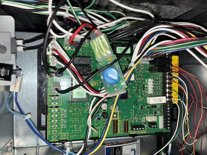 Completed comprehensive tune-up service on 11-year-old air conditioning system, including inspection of control board components, electrical connections, and outdoor condenser unit. Accessed and photographed interior control board showing all wiring harnesses, connectors, and circuit components in proper working condition. Removed outdoor unit access panel to inspect compressor motor, fan assembly, condenser coils, and verified all internal components operational with no visible damage or deterioration noted.