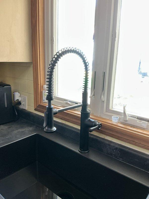 Completed full kitchen sink replacement and plumbing system upgrade. Removed existing sink and installed new Allen + Roth 33"x22" single bowl drop-in sink with black finish. Mounted and connected customer-supplied matte black faucet with coiled hose attachment, including installation of new shut-off valves and supply lines. Installed new black garbage disposal with matching disposal mount and electrical connection. Replaced all under-sink plumbing with new trap assembly and PVC drainage components. Drilled new drain line penetration through cabinet base as needed. In basement, removed existing rubber sand tee from 1-1/2" copper drain line and re-plumbed connection to vent stack using new PVC piping to ensure proper drainage and code compliance. All components tested and verified operational upon completion.