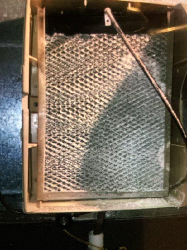 Completed MVP cooling maintenance visit on 9-year-old system. Inspected air handling unit and found air filter heavily loaded with dust and debris accumulation, restricting airflow through the honeycomb mesh surface. Performed electrical diagnostics on control board using digital multimeter to verify proper system operation and check voltage readings across multiple circuits. Documented equipment condition with photos showing filter status and control panel wiring configuration for maintenance records.