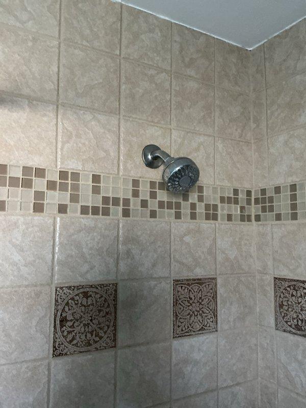 Replaced shower fixtures in bathroom with decorative tile surround. Customer provided new fixtures; verified cartridges were included with replacement components before proceeding with installation. Successfully removed existing chrome tub/shower faucet assembly and shower head, then installed new fixtures ensuring proper sealing and water flow functionality.