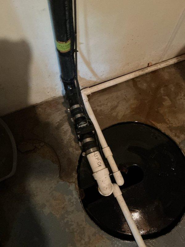 Responded to emergency call for sump pump discharge pipe separation causing basement flooding. Upon arrival, found the connection between the PVC discharge piping and vertical black discharge pipe had come apart, allowing water to spill directly onto the basement floor rather than being properly expelled outside. Reconnected and secured the separated discharge pipe sections, ensuring proper alignment and watertight seal at all joints. Tested the sump pump operation through multiple cycles to verify the discharge system was functioning correctly with no leaks. Confirmed water was being properly routed through the complete discharge assembly and exiting the building as designed.
