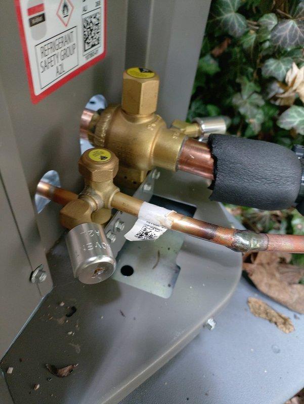 Completed installation of new air conditioning system with matching evaporator coil. Installed outdoor condensing unit with proper refrigerant line connections, brass service valves, and insulated suction line. Indoor air handler integrated with existing ductwork system, including reflective insulation on supply plenums and proper drainage connections established at outdoor unit location.