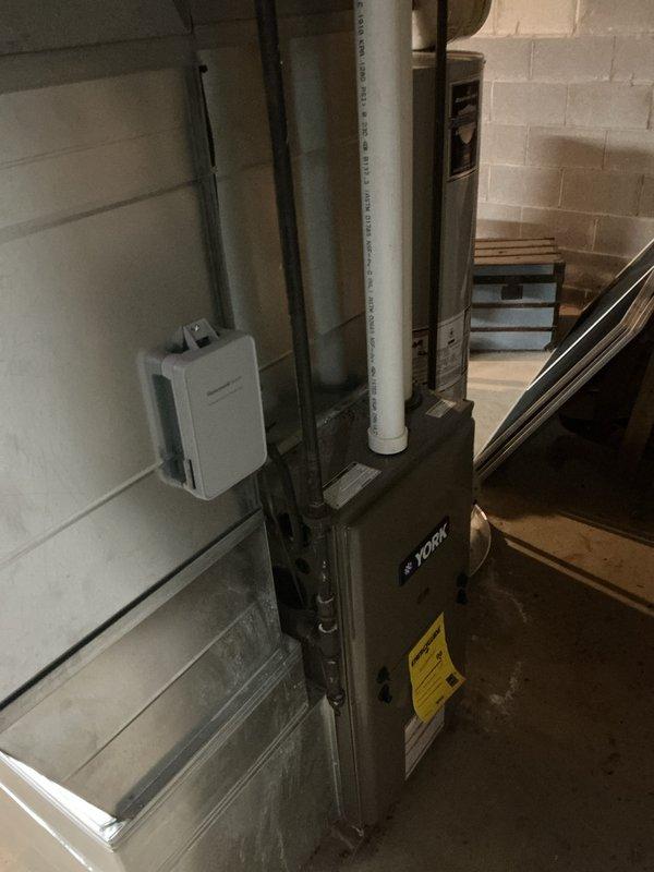 Completed installation of add-on air conditioning system with evaporator coil to existing York furnace in basement utility area. Installed new evaporator coil assembly, connected refrigerant lines, integrated condensate drain system with PVC piping, and mounted humidifier unit to furnace cabinet. All ductwork connections secured, system tested for proper operation, and installation verified to meet manufacturer specifications.