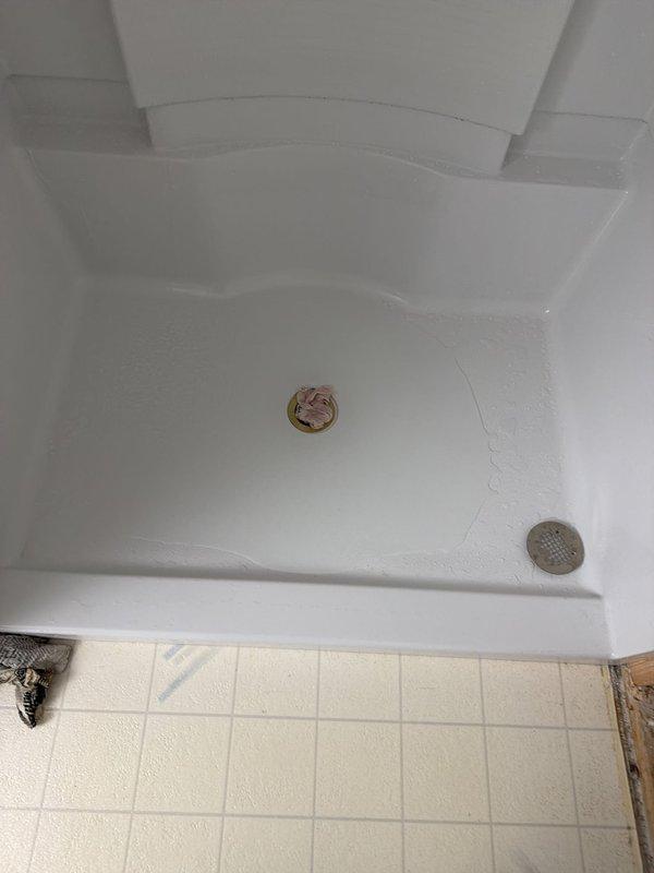 Completed installation of a new 48x36 center drain shower unit with fiberglass surround and integrated shelving recesses. Installed chrome handheld showerhead assembly and dual drain configuration with brass and chrome drain covers. Shower enclosure features molded corner construction with decorative tile border trim at upper perimeter. Unit was set on existing tile floor base with exposed framing prepared for final trim work completion.