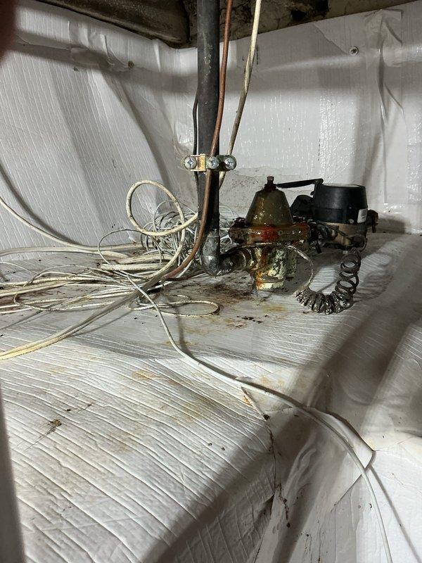 Responded to emergency call for active water line failure in basement. Upon arrival, found water pouring from compromised main line into basement area. Homeowner had already shut off main water supply to stop active flooding. Assessed crawl space and identified severely corroded pump assembly and valve components as source of failure. Inspected surrounding plumbing infrastructure including copper piping, valve assemblies, and pump connections, all showing significant age-related deterioration and corrosion. Documented extensive rust and patina buildup on mechanical components. Evaluated electrical wiring and connections in affected area for water damage. Photographed compromised equipment and surrounding conditions for repair assessment. Recommended main line repair or replacement to restore water service and prevent future failures.