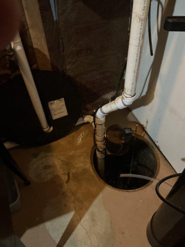 Provided complimentary second opinion assessment for customer-supplied sump pump installation in residential basement utility area. Evaluated existing sump pit configuration, including 18-24 inch diameter basin with standing water and current pump mechanism. Inspected PVC discharge piping, electrical connections, and surrounding concrete floor showing evidence of previous moisture intrusion and water staining. Assessed crawl space plumbing infrastructure and utility routing to determine optimal installation approach for new equipment. Documented current conditions including drainage patterns, structural framing clearances, and existing mechanical system placement to provide recommendations for proper sump pump installation.