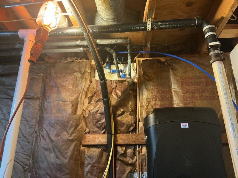 Provided complimentary second opinion assessment for customer-supplied sump pump installation in residential basement utility area. Evaluated existing sump pit configuration, including 18-24 inch diameter basin with standing water and current pump mechanism. Inspected PVC discharge piping, electrical connections, and surrounding concrete floor showing evidence of previous moisture intrusion and water staining. Assessed crawl space plumbing infrastructure and utility routing to determine optimal installation approach for new equipment. Documented current conditions including drainage patterns, structural framing clearances, and existing mechanical system placement to provide recommendations for proper sump pump installation.