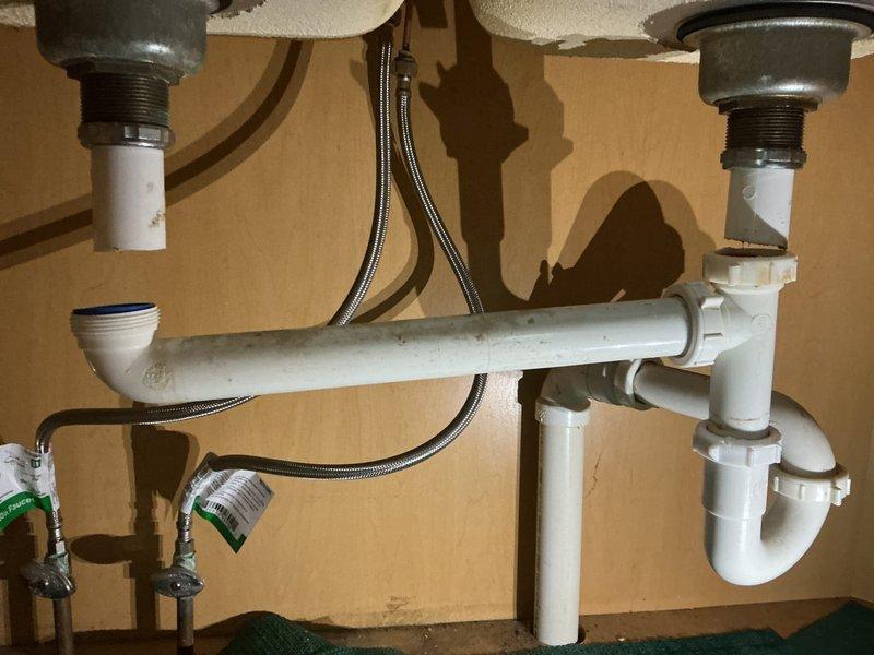 Responded to service call for leaking under kitchen sink. Upon inspection, identified loose tailpiece connections and cracked PVC piping in the P-trap assembly of double-sink drainage system. Tightened all threaded connections at basket strainers and tailpieces. Replaced damaged sections of white PVC drain pipe and P-trap components. Verified all supply line connections at shut-off valves were secure with no leaks present. Tested both drains under full water flow to confirm proper drainage and verified all connections remained dry and leak-free.