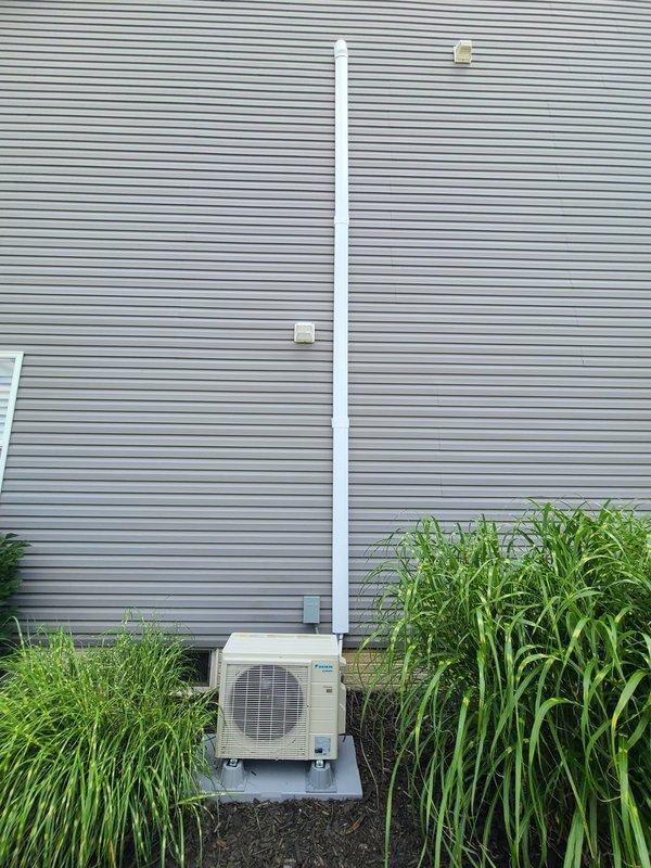 Completed installation of single-head ductless mini-split system with outdoor condenser unit mounted on concrete pad and refrigerant line set routed vertically along exterior wall. Installed disconnect box and associated electrical components, replaced damaged 25-amp fuse block that showed signs of electrical failure and burn damage between terminals.