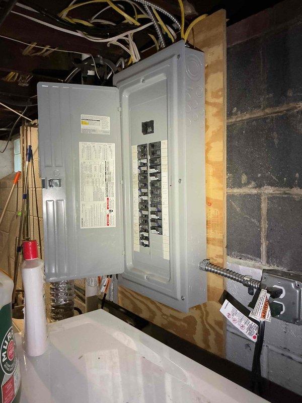 Responded to no power service call and installed new electrical service panel in basement utility area. Ran new electrical service line from exterior through trench to newly mounted panel box on interior wooden framing against concrete block wall. Panel installation included proper mounting, circuit breaker configuration in dual columns, and connection of all branch circuits with appropriate wire routing through flexible metal conduit to ceiling joists. Verified all connections, tested circuit functionality, and restored power to residence.