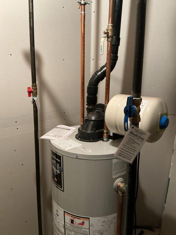 Responded to service call for water heater reported as failed but still operational. Upon inspection, found residential tanked water heater with expansion tank and recirculation pump installed in utility area. Unit appeared to be functioning with all plumbing connections intact, including copper supply lines, pressure relief valve, and black discharge piping properly routed. Verified expansion tank installation and circulator pump operation at base of unit. Documented existing system configuration showing standard residential setup with appropriate safety devices and plumbing code compliance. Equipment appeared operational at time of inspection with no visible leaks or immediate failure indicators present.
