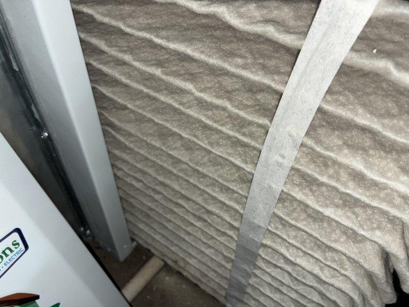 Performed comprehensive AC tune-up on 10-year-old air conditioning system. Inspected and documented condition of air filtration system, noting dust accumulation on pleated filter media with visible particulate buildup along creases. Examined electrical components including dual copper blade-style fuses in black plastic housing, verifying proper installation and functionality. System evaluated for operational efficiency and component wear consistent with unit age.