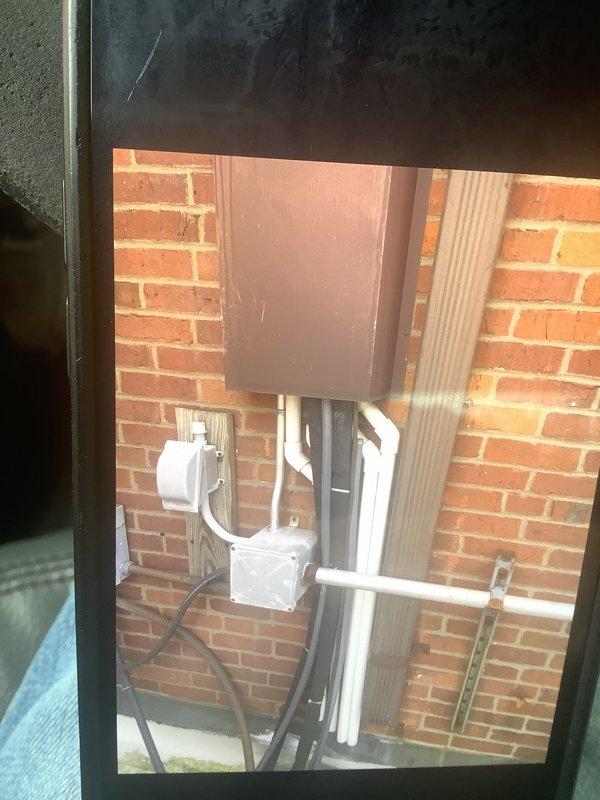 Conducted comprehensive assessment of commercial cooling system including rooftop air conditioning units and air handlers located in attic space above sanctuary area. Both rooftop AC units evaluated and determined to require full replacement due to operational failure and end-of-service-life conditions. Exterior condenser units inspected, showing significant age-related deterioration with visible weathering on concrete pad and surrounding infrastructure. Documented existing refrigerant line sets, electrical disconnects, and PVC piping configuration mounted on exterior brick wall for replacement planning. Photographed current equipment installation including dual condenser setup on concrete pad with associated electrical components and refrigerant piping. Prepared detailed estimate for complete system replacement of both rooftop units and coordinated ladder access requirements for attic air handler inspection and future installation work.