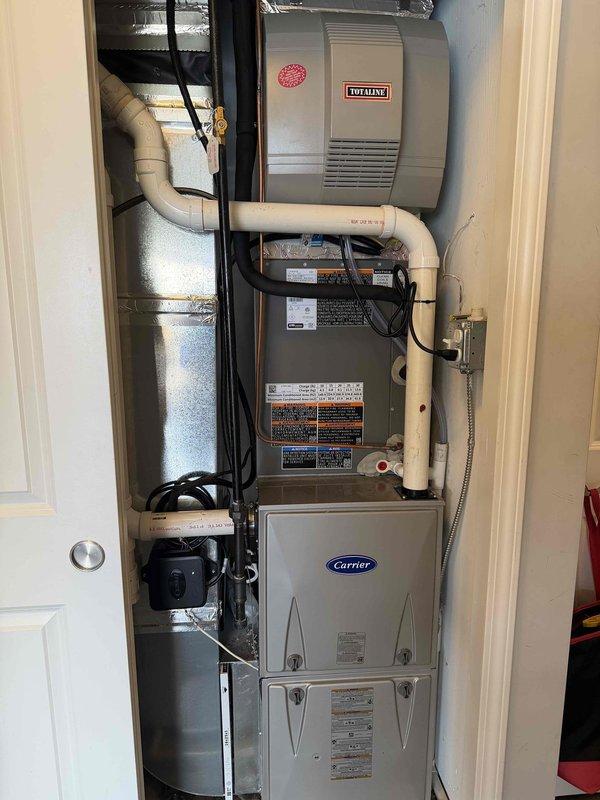 # HVAC System Installation and Electrical Component Replacement

Completed initial air conditioning and evaporator coil installation as part of a complete HVAC system setup in an interior utility closet. The installation included proper integration with existing furnace infrastructure, ensuring all components were properly mounted and secured according to manufacturer specifications.

Installed Carrier-branded furnace unit with corresponding air handler, establishing proper electrical connections and ductwork transitions. Integrated Totaline humidifier system at the upper section of the installation with appropriate silver ductwork routing and venting. Connected cream-colored PVC condensate drainage piping between system components to ensure proper moisture management and prevent water damage.

Verified all electrical connections and control wiring between components, including proper installation of flexible metallic conduit for code compliance. Mounted necessary electrical control bo