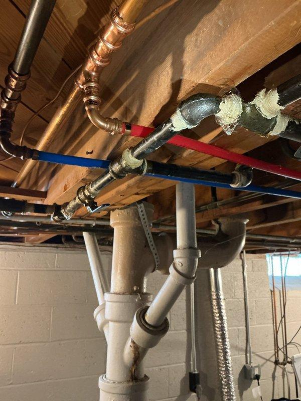 Responded to urgent gas leak investigation in 72-year-old residential property following gas company referral. Conducted comprehensive pressure testing and leak detection throughout plumbing system, focusing on aged copper piping infrastructure and corroded brass valve fittings located in attic/ceiling space. Identified significant oxidation and turquoise-green patina buildup on central valve assembly connecting multiple copper pipe sections, indicating advanced corrosion requiring immediate attention. Inspected basement mechanical room piping including copper lines, insulated pipes, and PVC drainage system to isolate leak source. Documented deteriorated valve condition and compromised connections affecting hot water availability.