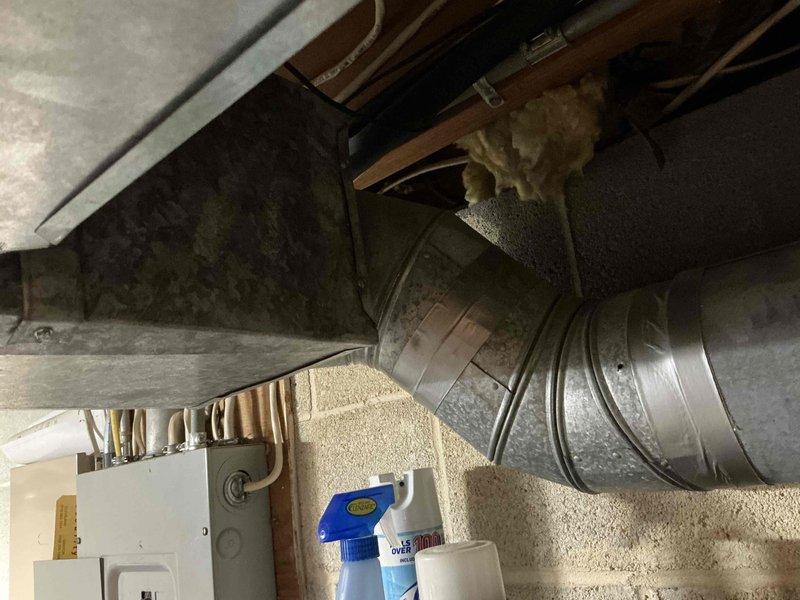Completed estimate for reworking main trunk ductwork serving approximately half of the residence. Assessed existing basement HVAC distribution system, including large flexible metallic duct connections, rectangular metal plenum transitions, and main trunk line routing through exposed ceiling joists. Documented current condition of ductwork showing dust accumulation and aging insulation. Evaluated integration with existing mechanical equipment including furnace unit and water heater. Photographed ductwork configuration, support systems, and clearances for comprehensive estimate preparation.