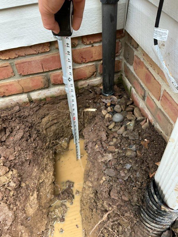 Assessed damaged underground electrical line to post light that was struck during sidewalk installation. Existing line was temporarily repaired but requires complete replacement to meet code requirements. Sidewalk company installed conduit at insufficient depth (3 inches); code requires 12-inch burial depth throughout run with GFCI protection.

Scope of work includes breaking out concrete surrounding existing post light fixture, which may require complete fixture replacement due to concrete damage. Will salvage light head if possible but post assembly likely compromised. New circuit will originate from right side of home near garage at existing line location. Installation plan: disconnect existing circuit inside home, install nail-on box with GFCI device at interior wall, exit home at same penetration point, run new underground line approximately 8 feet to relocated post light position clear of concrete sidewalk area. All excavated trenches will be backfilled; final landscaping grading