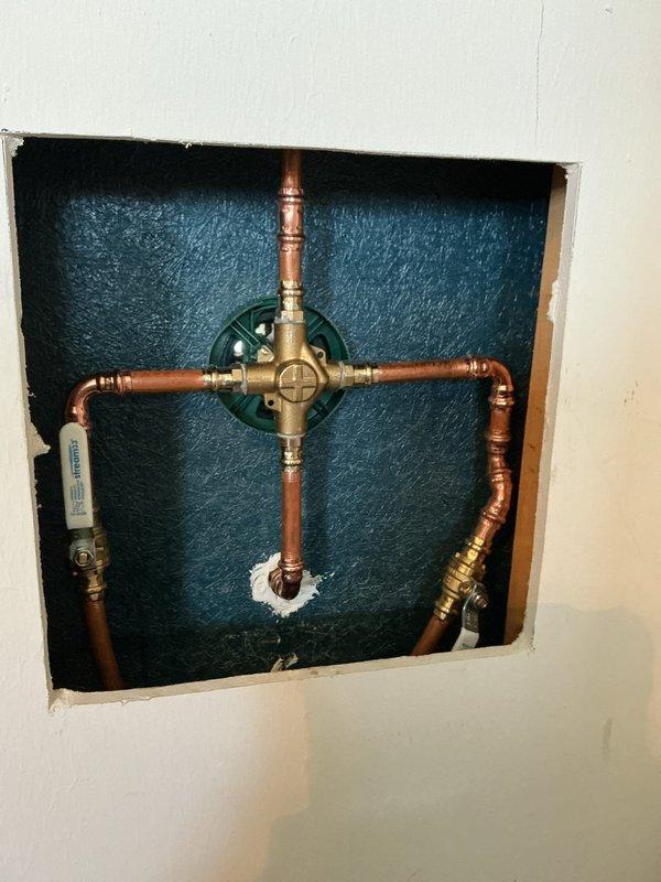 Replaced existing shower valve with new Moen single handle valve and chrome finish trim kit in second floor hall bathroom shower. Cut and installed access panel in closet behind shower wall for future service access. Removed old shower valve, installed new ball valves on supply lines, and connected new valve assembly to existing shower head riser pipe using copper piping and brass fittings.