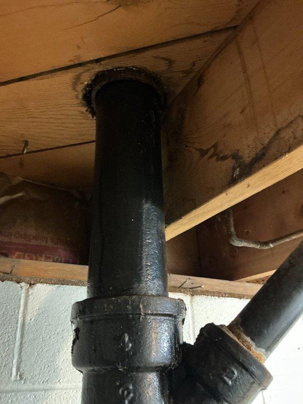 Responded to service call for toilet leak causing water to trickle down drain pipe and form puddles on basement floor. Inspected vertical cast iron waste stack in basement where pipe passes through floor joists, identifying leak at collar connection point during flush cycles. Examined under-sink plumbing and drain connections to assess overall drainage system condition in 70-year-old home. Documented existing pipe conditions including aged cast iron stack with visible corrosion at flanged joint section. Photographed leak source area and related plumbing infrastructure for assessment and recommended repairs to address water intrusion issue.