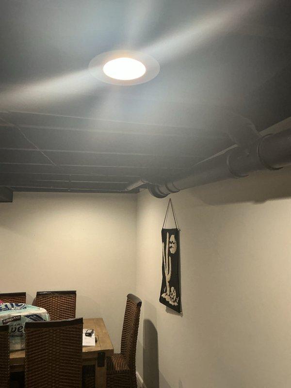 Completed electrical installation for septic system support in basement area with exposed ceiling infrastructure. Installed recessed lighting fixture and routed necessary wiring through exposed ceiling joists and ductwork to provide adequate illumination and power distribution for the finished living space below.
