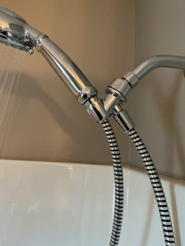 Responded to service call for malfunctioning handheld shower head with water leaking from multiple points at the wall connection and hose attachment to spray handle. Removed defective unit and installed new chrome-finished handheld shower head assembly with flexible metal hose and adjustable wall-mounted bracket. Tested installation to verify proper water flow and confirmed no leaks at connection points.