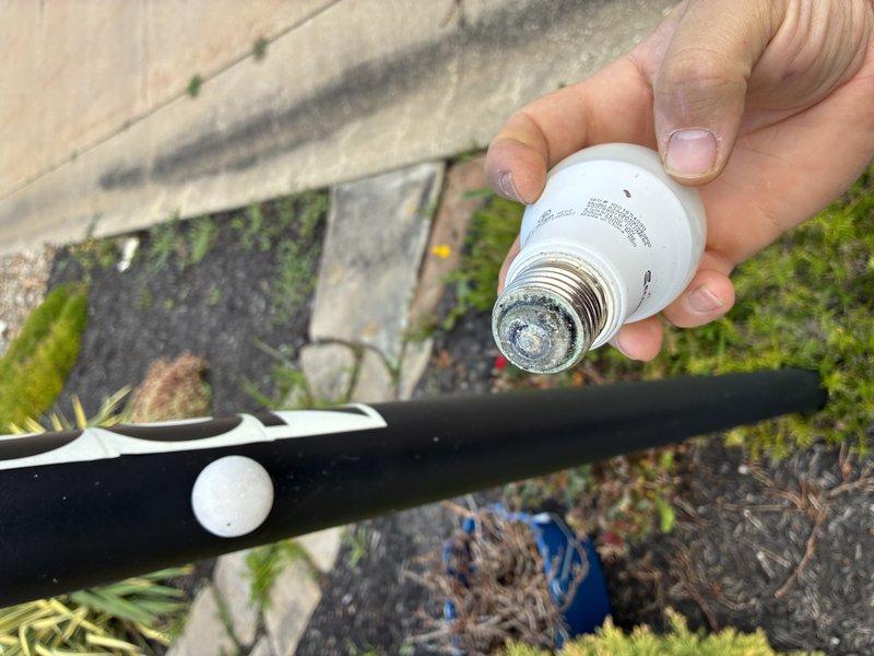 Responded to service call for bathroom circuit breaker repeatedly tripping. Upon inspection, identified corroded light bulb base with significant mineral buildup and deterioration at the socket connection, causing intermittent short circuit condition. Removed defective bulb, inspected fixture wiring and connections in exterior soffit area, verified all electrical components were secure and properly insulated. Replaced faulty bulb and confirmed circuit breaker reset successfully with no further tripping issues.
