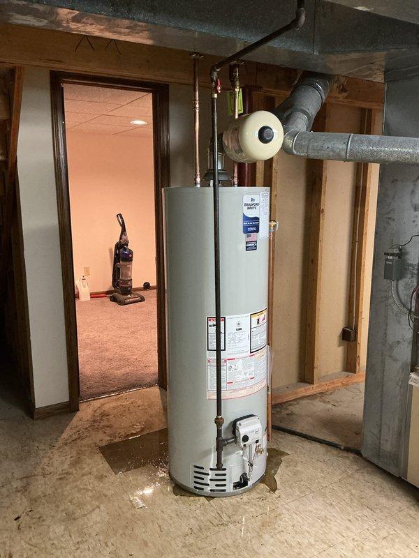 Replaced leaking water heater with new 40-gallon Bradford White natural gas automatic storage water heater including all required code upgrades. Installation included new ball valve, gas shut-off valve, proper electrical bonding of unit, and addition of thermal expansion tank to system. Unit installed with Category 1 natural draft venting per manufacturer specifications, copper supply lines with shutoff valves, and proper clearances in basement utility area.