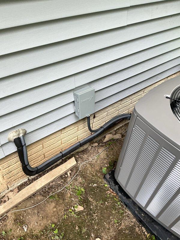 Completed full HVAC system replacement including outdoor condensing unit, evaporator coil, and refrigerant line set. Installed new gray condensing unit on concrete pad with proper clearances from building structure, mounted electrical disconnect box on exterior wall with conduit connection to unit, and secured new insulated refrigerant lines to building exterior using appropriate mounting brackets. System installed per manufacturer specifications and verified all electrical connections, refrigerant lines, and mounting hardware secure for warranty compliance.