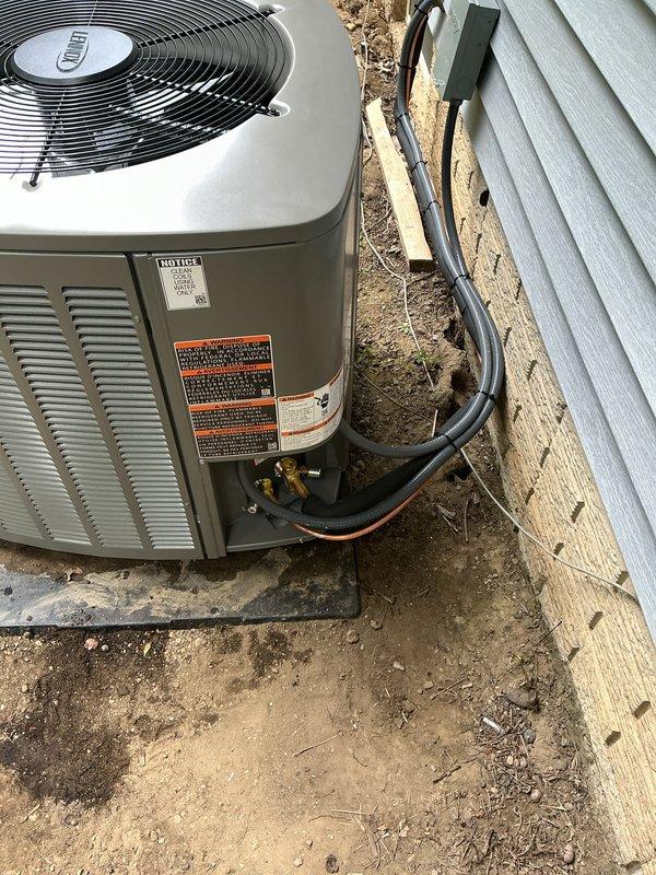 Completed full HVAC system replacement including outdoor condensing unit, evaporator coil, and refrigerant line set. Installed new gray condensing unit on concrete pad with proper clearances from building structure, mounted electrical disconnect box on exterior wall with conduit connection to unit, and secured new insulated refrigerant lines to building exterior using appropriate mounting brackets. System installed per manufacturer specifications and verified all electrical connections, refrigerant lines, and mounting hardware secure for warranty compliance.