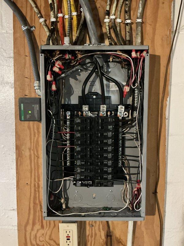 Completed full replacement of 150 amp electrical panel in unfinished interior space. Verified all existing grounding systems were up to code from recent generator installation, including copper wire connections to waterline and bonded tankless lines. Located and marked ground rod positions with flags for reference.

Installed new electrical panel with complete breaker replacement, including GFCI breaker and dual function breaker for enhanced protection. Routed and terminated all circuit wiring to new breakers, organizing black electrical wires in two vertical columns within the panel enclosure. Secured wire connections with appropriate connectors throughout the panel interior.

Coordinated main electrical feed connections at panel top, ensuring proper integration with existing conduits and PEX plumbing lines running through wall framing. Installed GFCI-protected outlet below panel on wooden stud framing. Completed panel labeling per code requirements. Work performed under permit with i