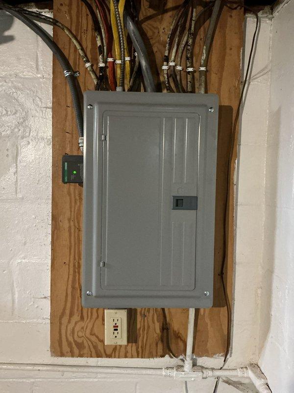 Completed full replacement of 150 amp electrical panel in unfinished interior space. Verified all existing grounding systems were up to code from recent generator installation, including copper wire connections to waterline and bonded tankless lines. Located and marked ground rod positions with flags for reference.

Installed new electrical panel with complete breaker replacement, including GFCI breaker and dual function breaker for enhanced protection. Routed and terminated all circuit wiring to new breakers, organizing black electrical wires in two vertical columns within the panel enclosure. Secured wire connections with appropriate connectors throughout the panel interior.

Coordinated main electrical feed connections at panel top, ensuring proper integration with existing conduits and PEX plumbing lines running through wall framing. Installed GFCI-protected outlet below panel on wooden stud framing. Completed panel labeling per code requirements. Work performed under permit with i