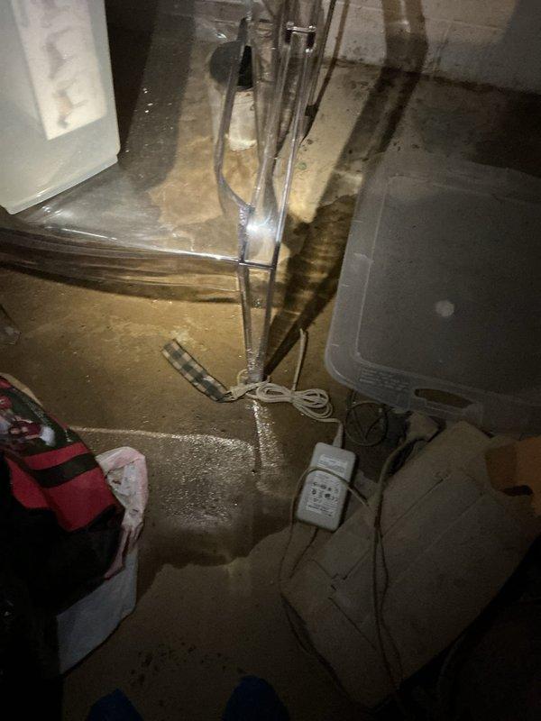 Responded to toilet leak at base with water accumulating on basement floor. Upon arrival, confirmed active water leakage despite shut-off valve being closed, indicating supply line or valve failure rather than toilet seal issue. Documented extensive water damage on concrete basement floor with visible pooling and moisture stains throughout the area. Assessed mechanical room conditions and surrounding equipment exposure to water. Photographed affected areas showing water accumulation near water heater and other utilities. Shut off main water supply to prevent further flooding and recommended immediate replacement of faulty shut-off valve and inspection of toilet mounting flange and wax ring seal.