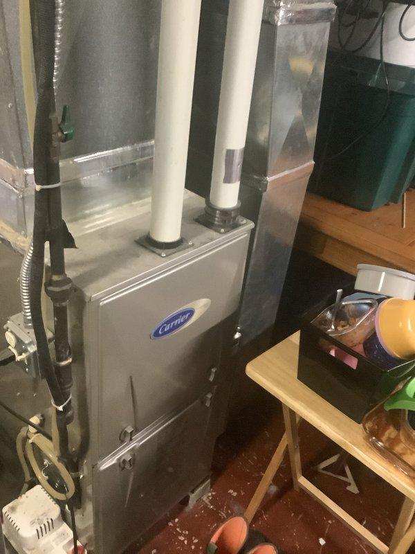 Conducted air conditioning replacement estimate for a 20-year-old system with existing Carrier furnace installation. Documented current HVAC equipment configuration including furnace unit with PVC venting and ductwork connections in basement utility area. Provided quote for replacement system to customer.