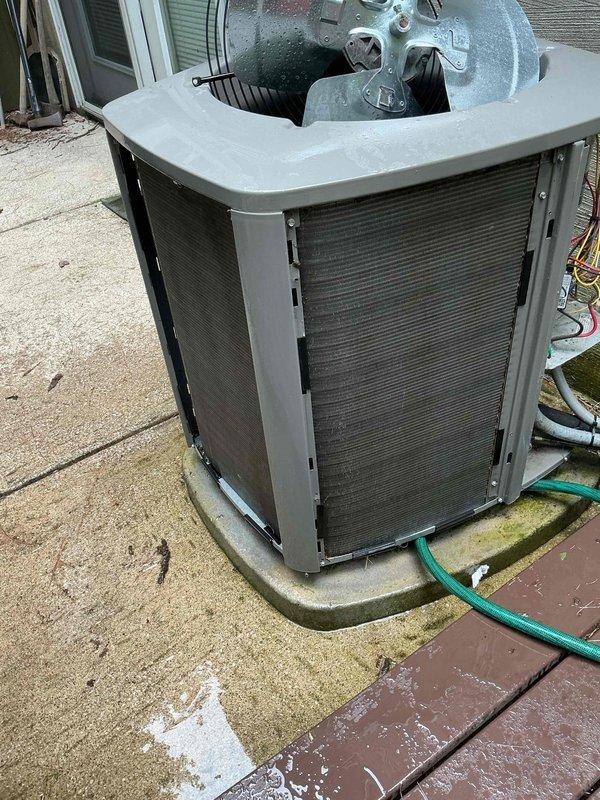 Completed MVP cooling maintenance visit on 6-year-old system located outside basement door. Upon inspection, discovered damaged wiring at contactor with exposed and frayed copper conductors on red power wire, presenting potential safety hazard and operational risk. Documented equipment condition with photos showing outdoor condenser unit on concrete pad and electrical connection assembly with compromised wiring requiring future repair or replacement to ensure safe system operation.
