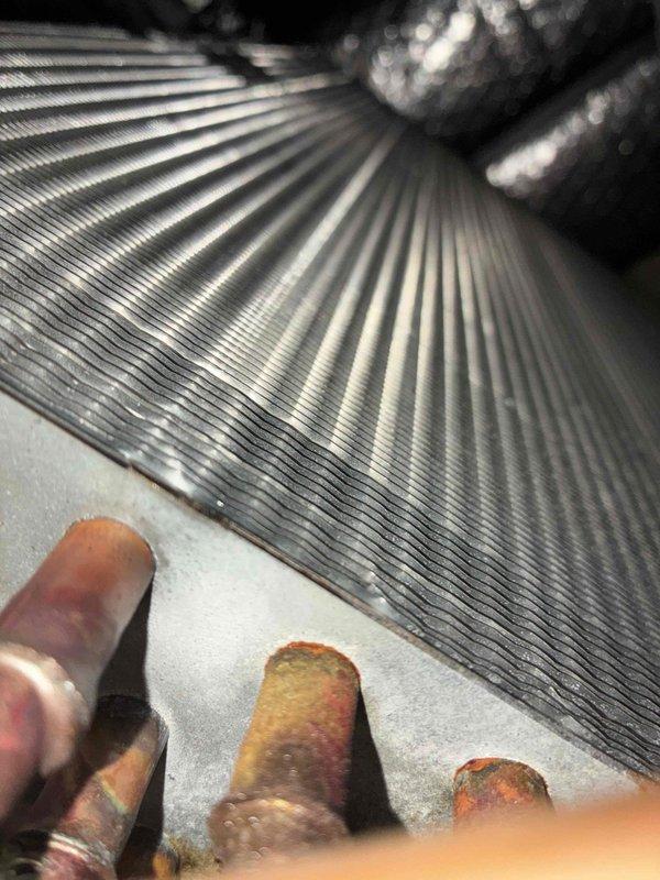 Performed comprehensive air conditioning tune-up on 3-year-old system. Removed condenser unit casing and discovered heavy accumulation of dirt, dust, lint, and debris obstructing the condenser coil fins, significantly impacting airflow and heat transfer efficiency. Thoroughly cleaned condenser coil assembly, removing matted fibrous material and debris buildup from coil surfaces and fins. Inspected internal components including heat exchanger and finned coil unit, which displayed proper structural integrity with regular fin spacing maintained. Restored unit to optimal operating condition, improving airflow and system efficiency. All components inspected and functioning properly upon completion of routine maintenance service.