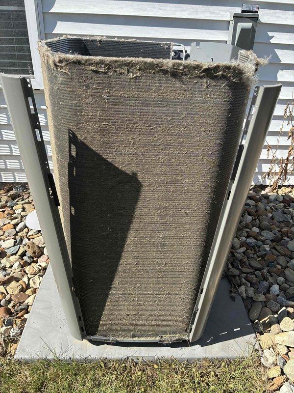 Performed comprehensive air conditioning tune-up on 3-year-old system. Removed condenser unit casing and discovered heavy accumulation of dirt, dust, lint, and debris obstructing the condenser coil fins, significantly impacting airflow and heat transfer efficiency. Thoroughly cleaned condenser coil assembly, removing matted fibrous material and debris buildup from coil surfaces and fins. Inspected internal components including heat exchanger and finned coil unit, which displayed proper structural integrity with regular fin spacing maintained. Restored unit to optimal operating condition, improving airflow and system efficiency. All components inspected and functioning properly upon completion of routine maintenance service.