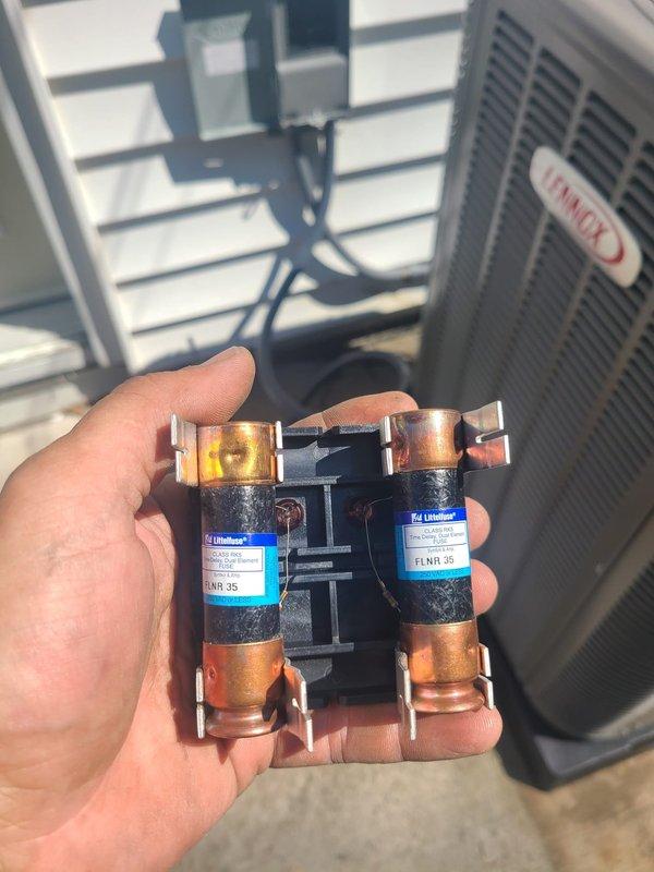 Completed installation of new Carrier air conditioning system with evaporator coil in residential basement utility room. Installed outdoor condensing unit on rooftop with proper refrigerant line connections, verified electrical connections with dual 35-amp Littelfuse FLNR fuses, and connected PVC condensate drainage system to existing furnace plenum. System tested and operational.