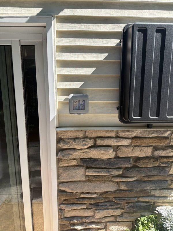 Replaced six exterior light fixtures with customer-supplied units, including two sconces at the front door, one sconce at the garage man door, one floodlight over the patio sliding glass door, one sconce at the deck sliding glass door, and one floodlight above the deck. Installed two new exterior outlets with GFCI protection and weatherproof in-use covers: one two-gang outlet near the patio TV location by tapping into an existing three-gang switch box with constant power, and one two-gang outlet near the patio storage box by fishing wire through the wall cavity from an existing garage outlet. Replaced the garage-side outlet during the installation process to ensure proper access and code compliance. Performed voltage testing on the existing post light to diagnose operational issues and determine repair requirements.