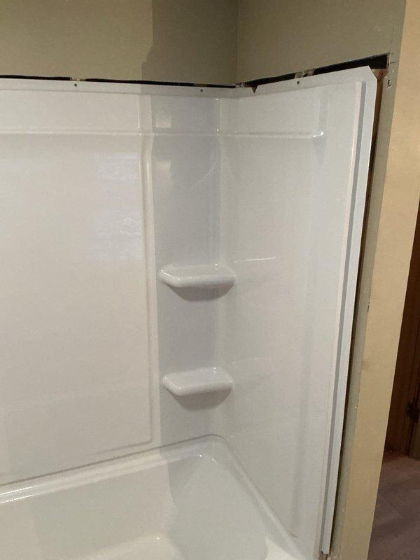 Installed a 30x60 white fiberglass bathtub and shower surround unit with integrated soap dishes and built-in threshold. Accessed and connected drain lines by opening the ceiling below the installation area, with customer acknowledgment that drywall repair is not included in scope of work. Completed installation with proper trim work and sealing after parts arrived and were available for use.