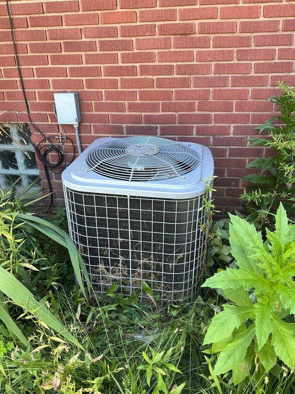 Responded to service call for air conditioning system not performing adequately. Upon arrival, performed maintenance visit protocol and system condition assessment. Inspected outdoor condenser unit located against building exterior, noting vegetation overgrowth around base requiring clearance for proper airflow. Examined electrical components and discovered significant spider web accumulation on terminal connections, wiring, and capacitor assembly, which can impede electrical connections and system performance. Cleaned electrical panel, removed debris and cobwebs from terminal block and wire connections, and verified all electrical connections were secure. Cleared vegetation from around condenser unit to restore proper airflow and prevent future airflow restrictions. System operational following cleaning and maintenance procedures.